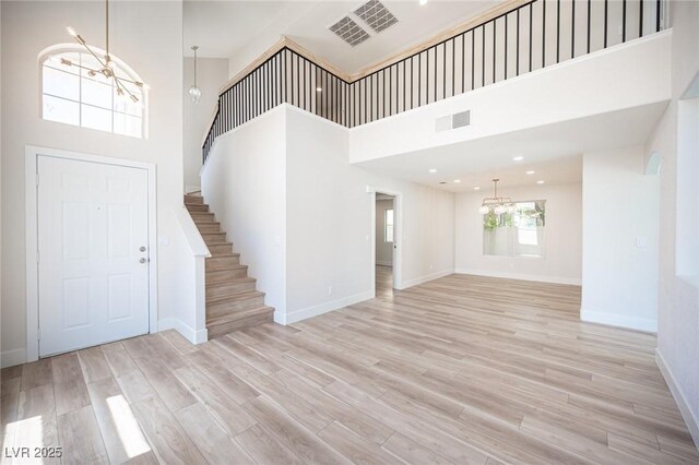 1620 Western Lily St, Las Vegas, NV 89128 - unfurnished living room featuring a chandelier, a high ceiling, stairs, baseboards, and wood finished floors