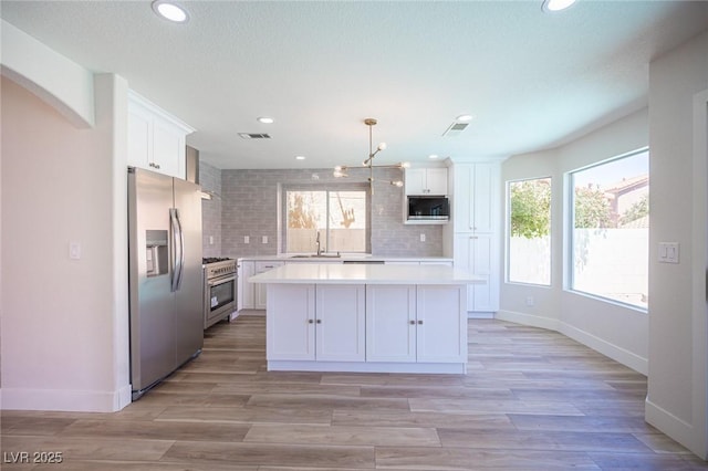 1620 Western Lily St, Las Vegas, NV 89128 - kitchen with appliances with stainless steel finishes, light countertops, white cabinets, backsplash, and healthy amount of natural light