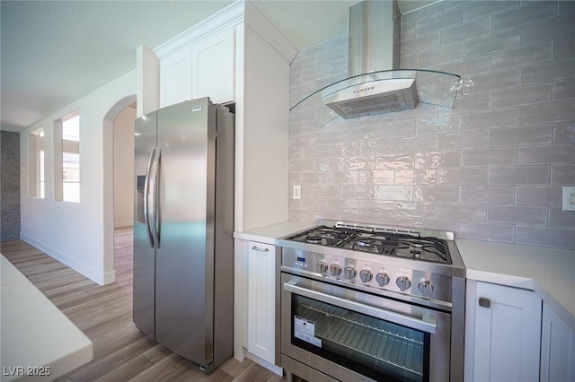 1620 Western Lily St, Las Vegas, NV 89128 - kitchen featuring appliances with stainless steel finishes, wall chimney exhaust hood, arched walkways, and light countertops