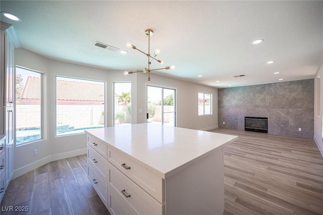 1620 Western Lily St, Las Vegas, NV 89128 - kitchen featuring light wood-type flooring, recessed lighting, a tiled fireplace, white cabinets, and a chandelier