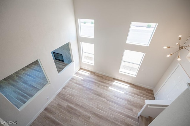 1620 Western Lily St, Las Vegas, NV 89128 - unfurnished living room with a chandelier, wood finished floors, a high end fireplace, a towering ceiling, and baseboards