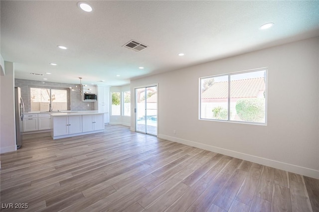 1620 Western Lily St, Las Vegas, NV 89128 - unfurnished living room featuring baseboards, light wood finished floors, recessed lighting, and a sink