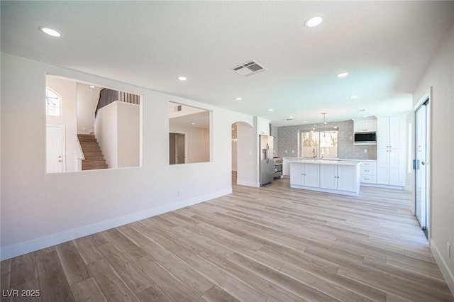 1620 Western Lily St, Las Vegas, NV 89128 - unfurnished living room featuring light wood-type flooring, a sink, arched walkways, baseboards, and recessed lighting