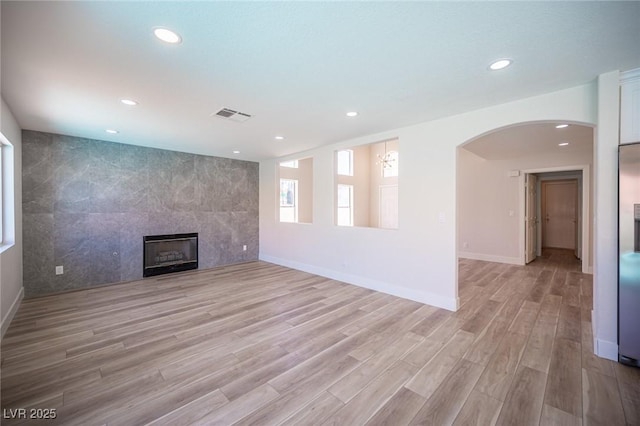 1620 Western Lily St, Las Vegas, NV 89128 - unfurnished living room featuring a tile fireplace, light wood-style floors, recessed lighting, arched walkways, and baseboards