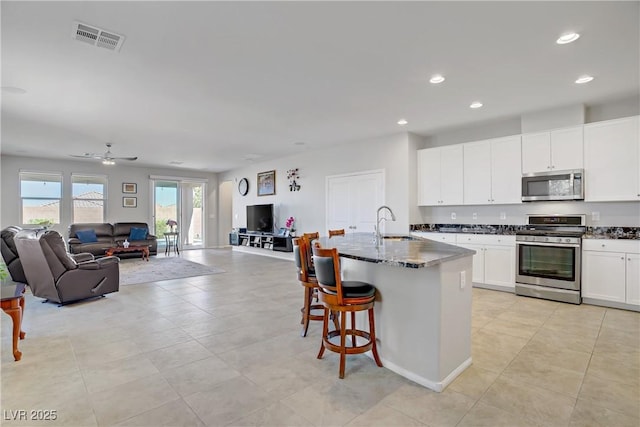 748 Dellenbaugh Ct, Las Vegas, NV 89178 - kitchen with appliances with stainless steel finishes, open floor plan, a sink, recessed lighting, and dark stone countertops