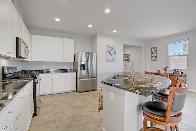 748 Dellenbaugh Ct, Las Vegas, NV 89178 - kitchen with appliances with stainless steel finishes, a sink, a breakfast bar, dark stone counters, and a center island with sink