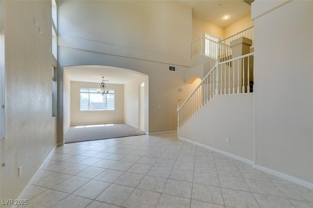 foyer featuring arched walkways, stairway, tile patterned flooring, a towering ceiling, and a chandelier