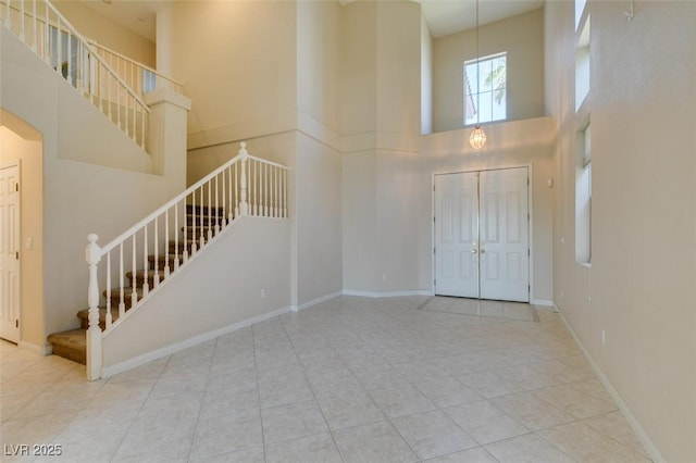 tiled entryway with a towering ceiling, stairway, arched walkways, and baseboards