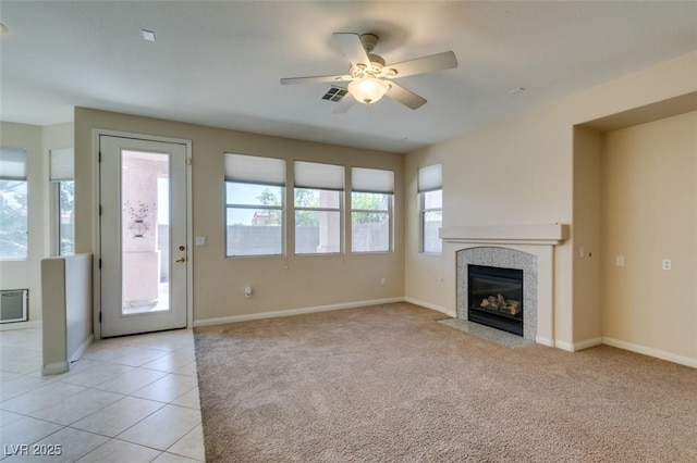 unfurnished living room with ceiling fan, baseboards, light tile patterned floors, and light colored carpet