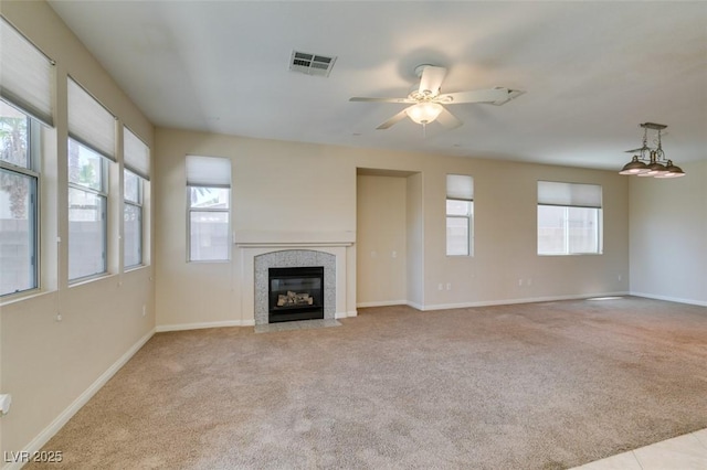 unfurnished living room with carpet flooring, a tiled fireplace, a ceiling fan, and baseboards