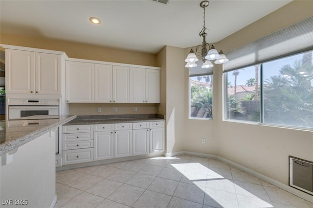 kitchen with white oven, white cabinets, light tile patterned floors, a chandelier, and decorative light fixtures