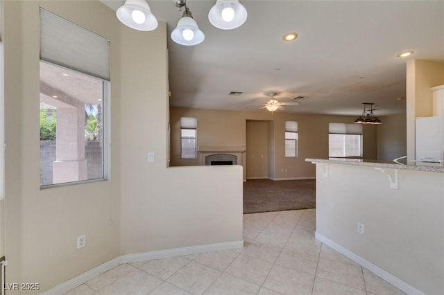 kitchen with healthy amount of natural light, a ceiling fan, fridge, baseboards, and recessed lighting
