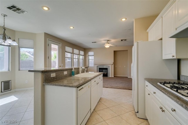 kitchen with white appliances, a sink, a high end fireplace, an island with sink, and ceiling fan
