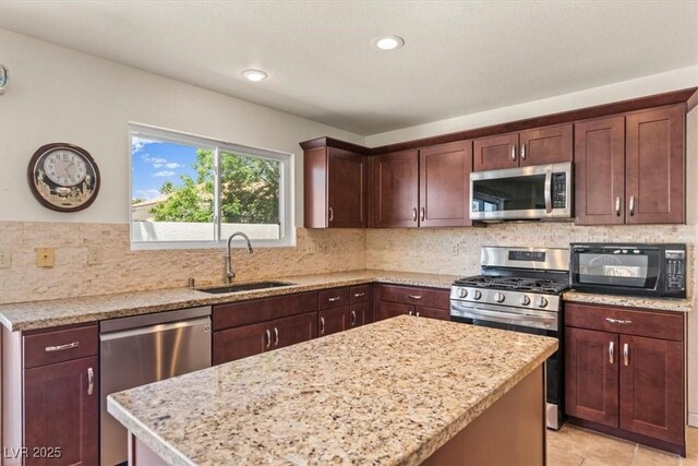 2024 Spruce Brook Dr, Henderson, NV 89074 - kitchen with appliances with stainless steel finishes, a sink, a center island, decorative backsplash, and light stone countertops