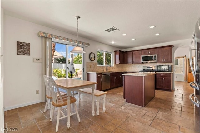 2024 Spruce Brook Dr, Henderson, NV 89074 - kitchen featuring appliances with stainless steel finishes, a kitchen island, decorative backsplash, recessed lighting, and stone tile floors