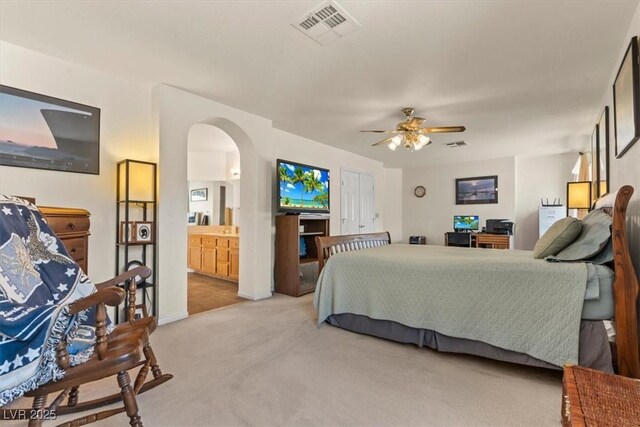 2024 Spruce Brook Dr, Henderson, NV 89074 - bedroom with light carpet, arched walkways, ceiling fan, ensuite bath, and baseboards