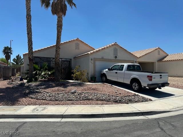 view of front of property featuring an attached garage, driveway, stucco siding, and a tiled roof