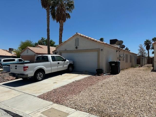 view of side of property featuring an attached garage, concrete driveway, and stucco siding