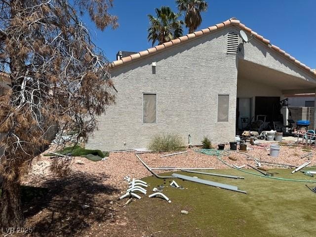 back of property with a tiled roof and stucco siding