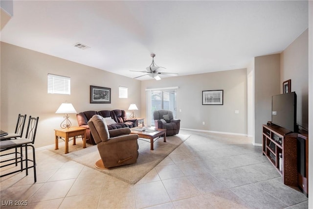 living area featuring a ceiling fan, light tile patterned flooring, and baseboards