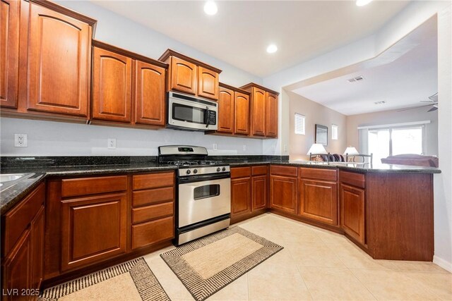 kitchen featuring appliances with stainless steel finishes, a peninsula, recessed lighting, dark stone countertops, and brown cabinets