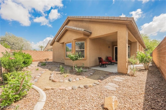 rear view of property featuring a patio area, stucco siding, and a fenced backyard