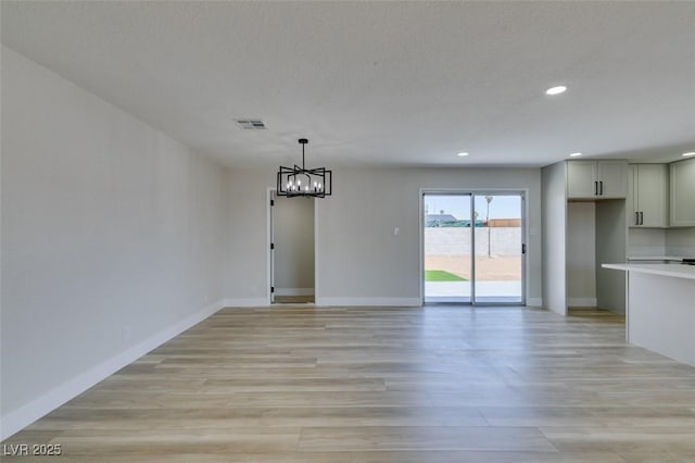 unfurnished dining area featuring recessed lighting, a chandelier, light wood-type flooring, and baseboards