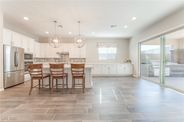 kitchen with stainless steel appliances, light countertops, recessed lighting, wood finish floors, and white cabinetry