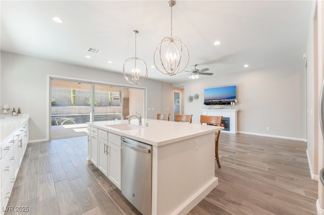 kitchen featuring a sink, dishwasher, a chandelier, light wood-type flooring, and white cabinets