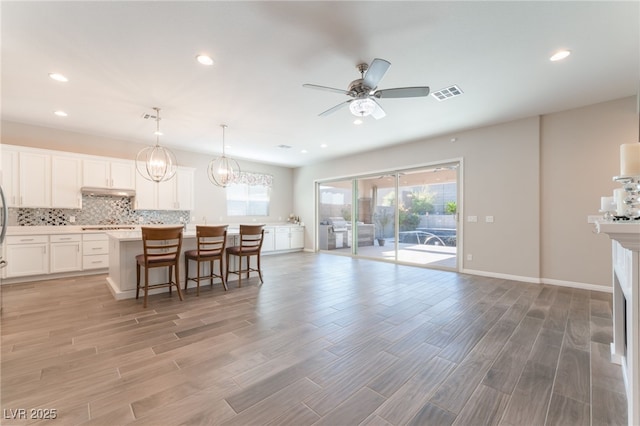 kitchen with ceiling fan, light wood-style floors, tasteful backsplash, a kitchen island, and recessed lighting