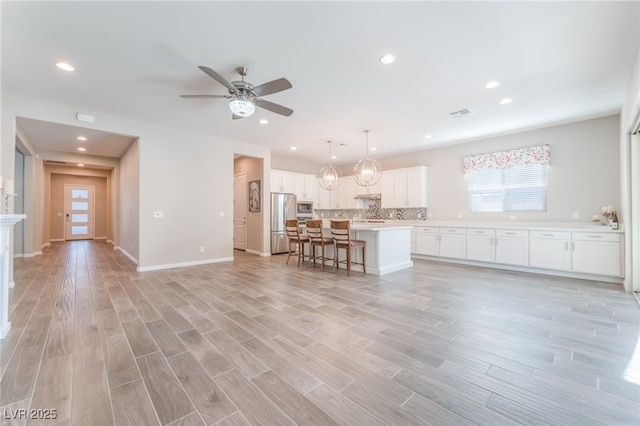 living area with ceiling fan, recessed lighting, light wood-style flooring, and baseboards