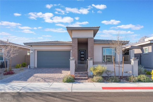 view of front of home with stucco siding, an attached garage, and decorative driveway