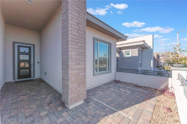 view of exterior entry featuring stucco siding and a patio
