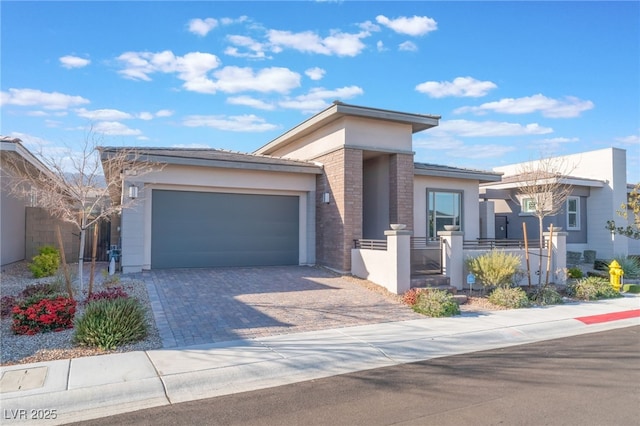 view of front of home featuring decorative driveway, stucco siding, a garage, and a fenced front yard
