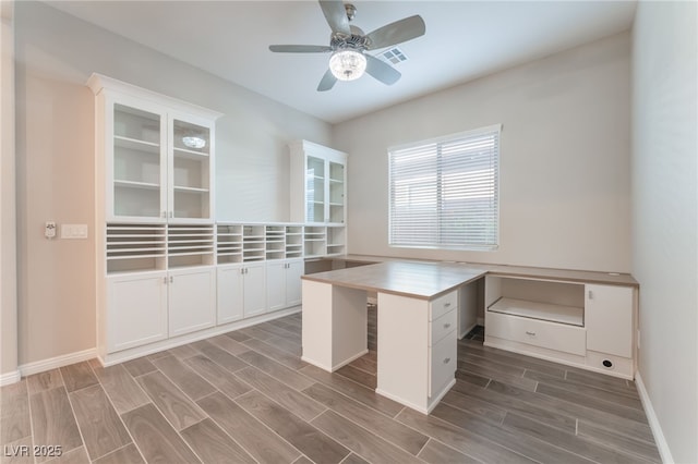 unfurnished office with wood finished floors, ceiling fan, and baseboards