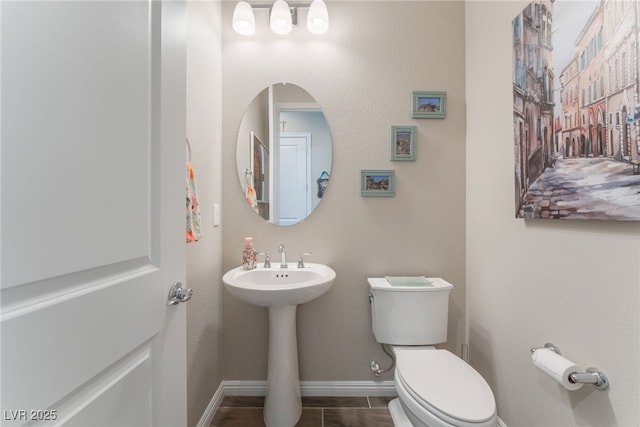 half bathroom with baseboards, toilet, tile patterned flooring, and a sink