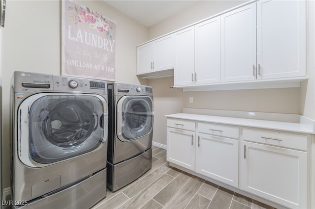 laundry area with separate washer and dryer, cabinet space, wood tiled floors, and baseboards