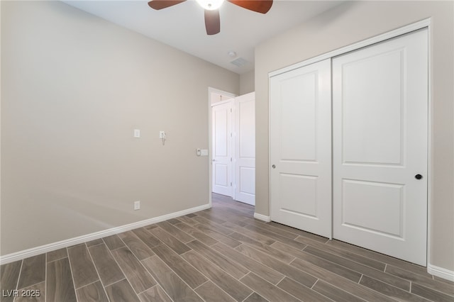 unfurnished bedroom featuring wood finish floors, baseboards, and a closet