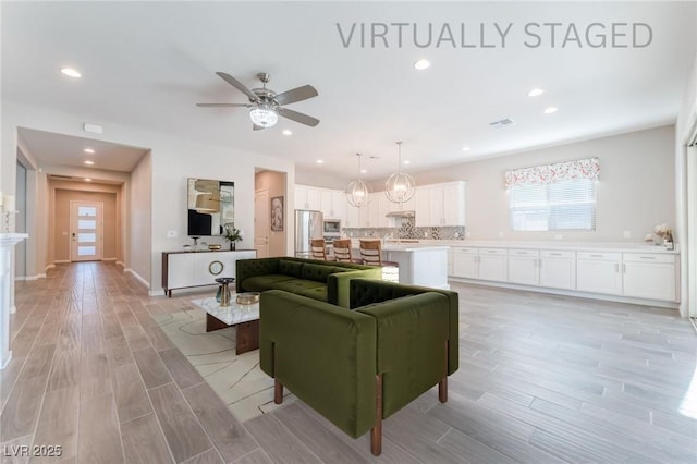 living area with light wood-type flooring, a ceiling fan, and recessed lighting