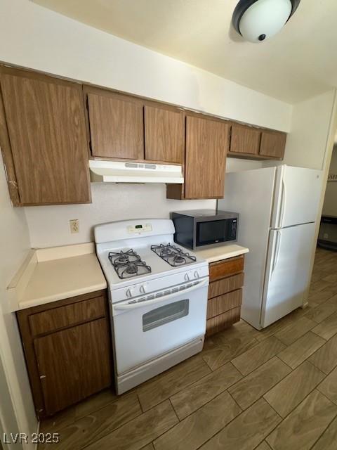 4820 Mahogany Dr, Las Vegas, NV 89110 - kitchen with under cabinet range hood, white appliances, light countertops, and brown cabinets