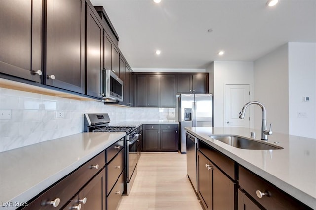 kitchen featuring stainless steel appliances, a sink, dark brown cabinets, recessed lighting, and light countertops