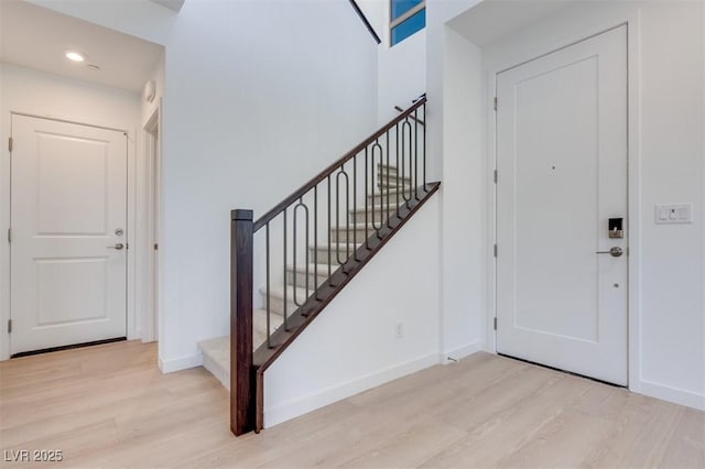 entryway featuring wood finished floors, baseboards, stairs, and recessed lighting