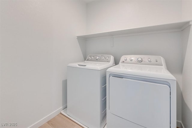 clothes washing area featuring washer and clothes dryer, baseboards, and light wood-style flooring