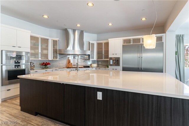 3458 W Agate Ave, Las Vegas, NV 89139 - kitchen featuring wall chimney range hood, appliances with stainless steel finishes, light countertops, tasteful backsplash, and modern cabinets