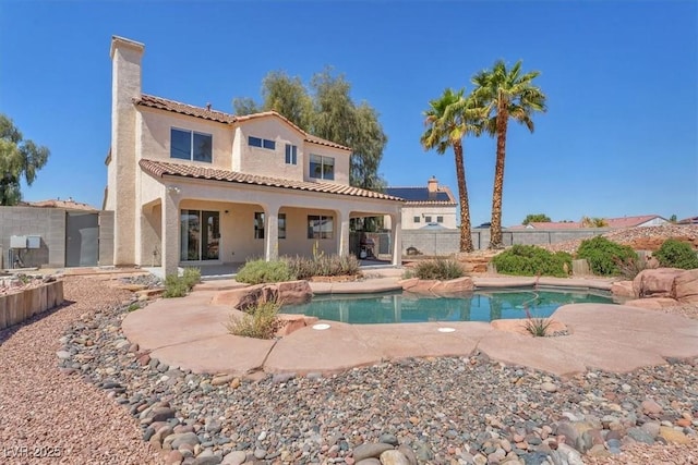 rear view of house with stucco siding, a chimney, a tiled roof, and a patio area