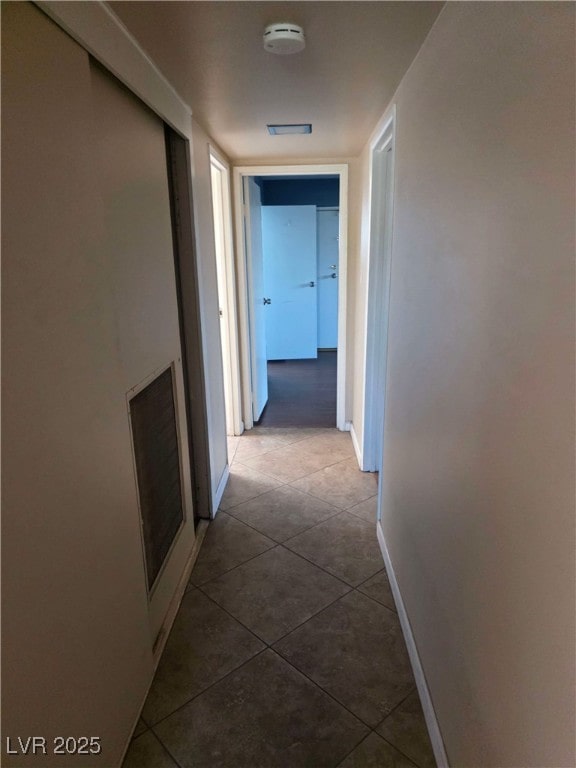 hallway with dark tile patterned floors and baseboards