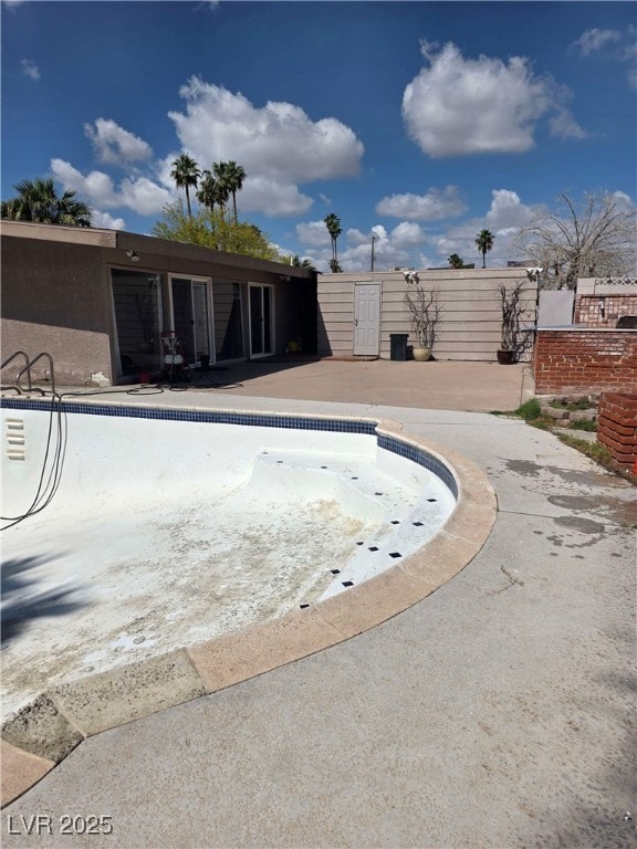 view of swimming pool with fence and an empty pool