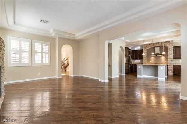11228 Hedgemont Ave, Las Vegas, NV 89138 - unfurnished living room featuring a tray ceiling, arched walkways, and dark wood-style flooring