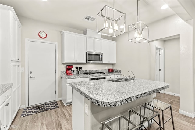 160 Lomita Heights Dr, Las Vegas, NV 89138 - kitchen with stainless steel microwave, light wood-type flooring, and white cabinets