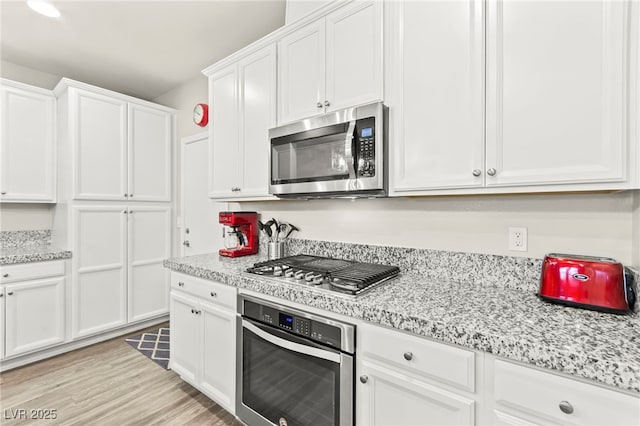 160 Lomita Heights Dr, Las Vegas, NV 89138 - kitchen with stainless steel appliances, white cabinets, light wood-type flooring, and light stone counters